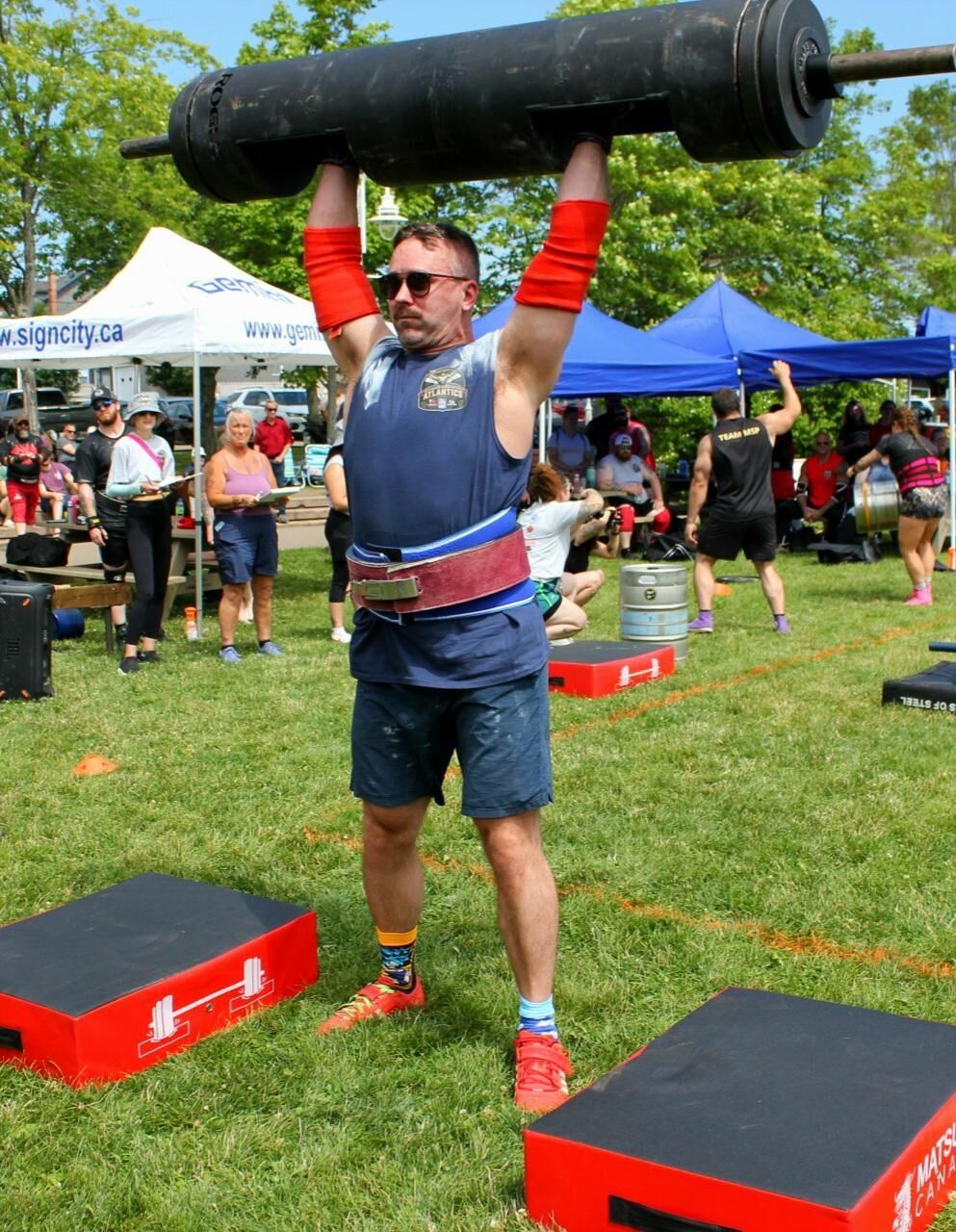 Josh Dunbar pressing a log overhead at an outdoor strongman competition