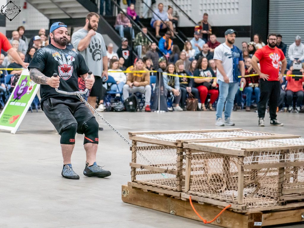 Strongman athlete pulling a sled in front of a crowd